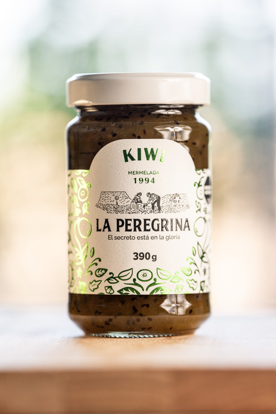 Frasco de mermelada de kiwi Clásica 1994 sobre una mesa de madera, con el jardín de fondo