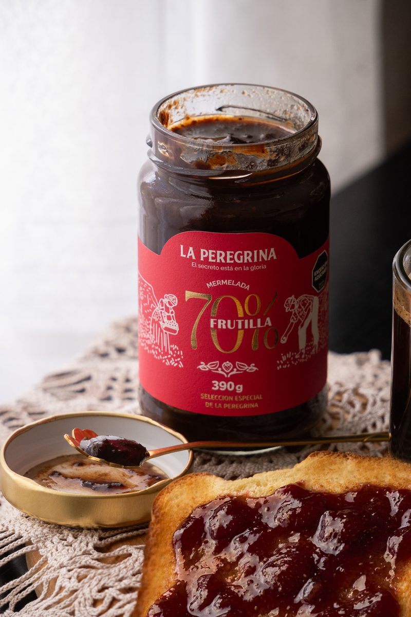 Frasco de mermelada de frutilla 70% junto a una tostada untada